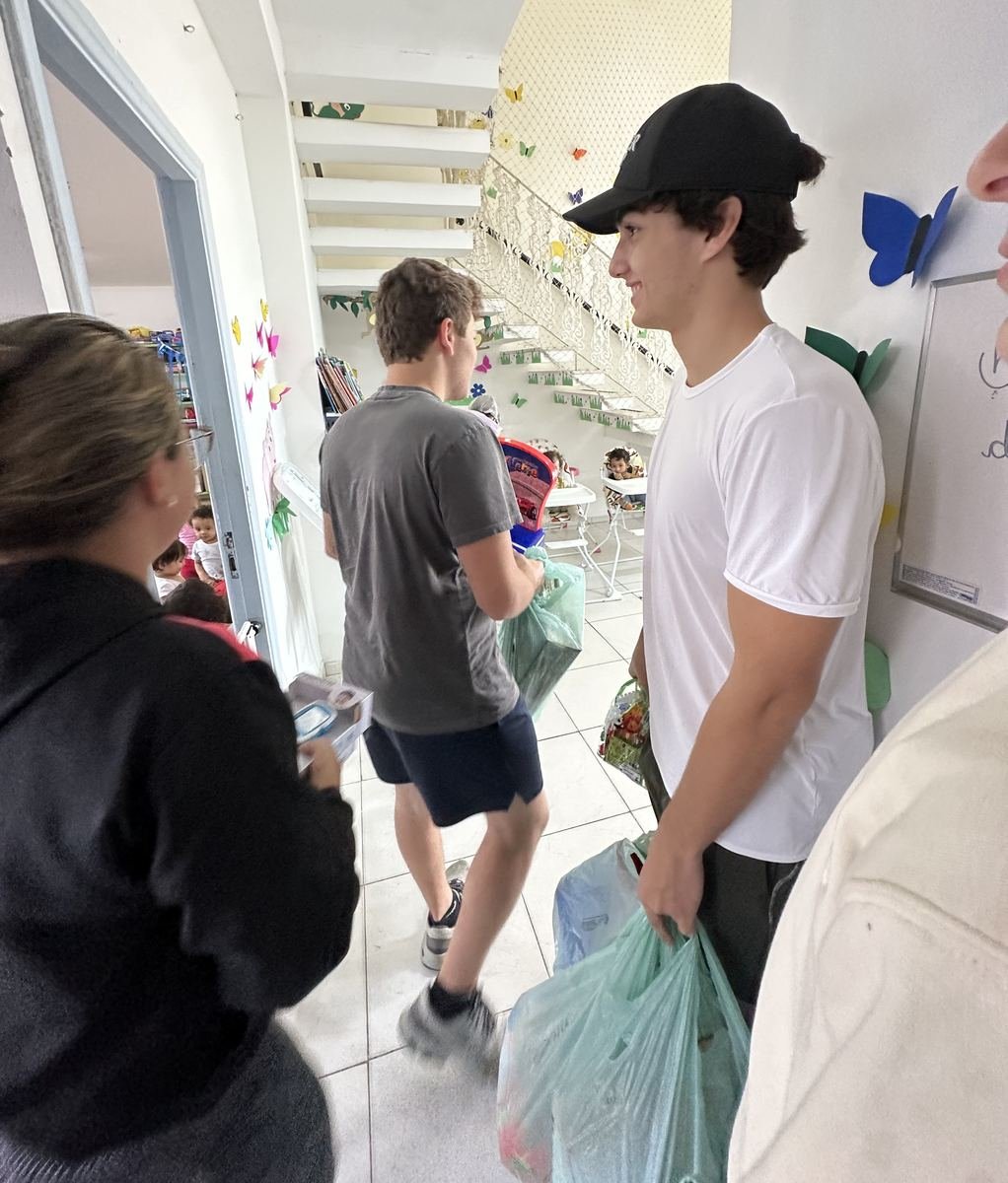 Two leaders walking into a daycare carrying bags of toys