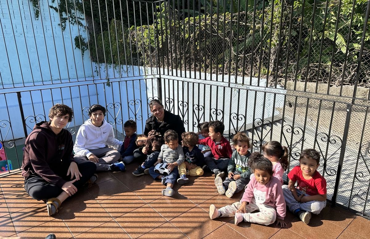 The founders sitting with daycare children on the first visit in 2023