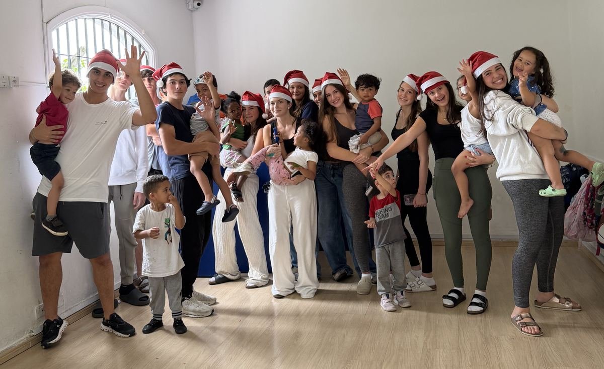 Rise Up Co members in Santa hats with children from the daycare at the December 2025 Christmas visit